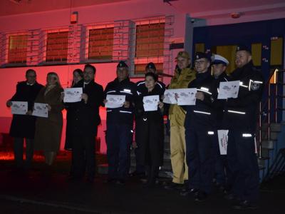 Wejście do Komendy Powiatowej Policji w Szydłowcu oświetlone czerwonym światłem
na zdjęciu również Policjanci, Strażacy, Starosta Szydłowiecki, Wicestarosta Szydłowiecki, Burmistrz Szydłowca, Wiceburmistrz Szydłowca - zdjęcie 2