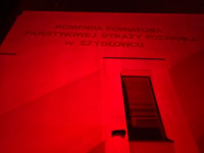 Wejście do Komendy Powiatowej Straży Pożarnej w Szydłowcu oświetlone czerwonym światłem 