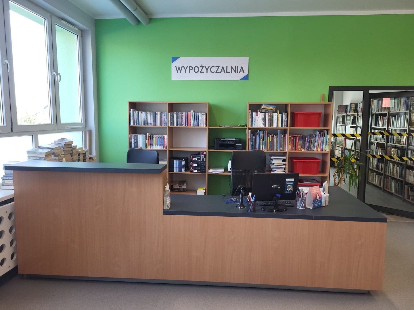 Zdjęcie wypożyczalni biblioteki. Na zdjęciu znajduje się lada biblioteczna. [2000x1500]