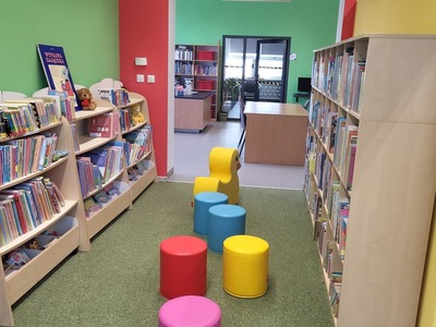 Na zdjęciu jest księgozbiór biblioteki oraz pufy dla dzieci.