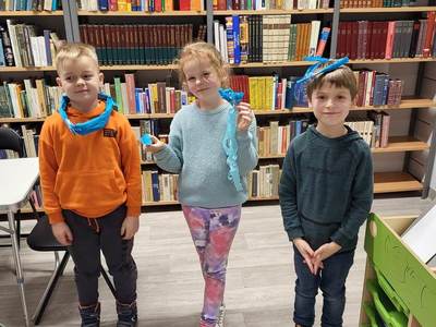 Na zdjęciu znajdują się uczestnicy zajęć. W tle księgozbiór biblioteki.