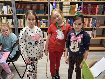 Na zdjęciu znajdują się uczestnicy zajęć. W tle księgozbiór biblioteki.