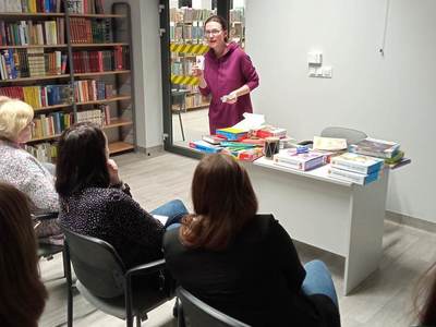Na zdjęciu znajduje się Pani Pedagog, która pokazuje książki wspierające naukę czytania i pisania.