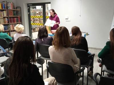 Na zdjęciu znajduje się Pani Pedagog, która pokazuje książki wspierające naukę czytania i pisania.