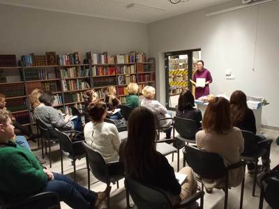 Na zdjęciu znajduje się Pani Pedagog, która pokazuje książki wspierające naukę czytania i pisania.