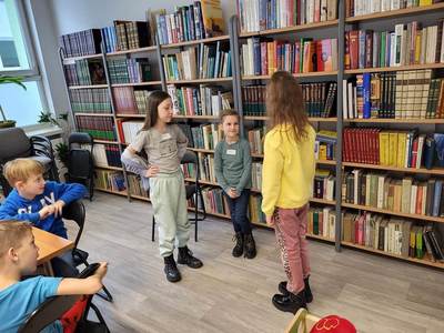Zdjęcie przedstawia dzieci uczęszczające na warsztaty. Dzieci stoją i wykonują powierzone im zadania.