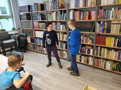 Zdjęcie przedstawia dzieci uczęszczające na warsztaty. Dzieci stoją i wykonują powierzone im zadania.