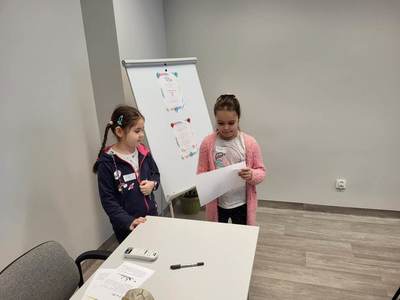 Zdjęcie przedstawia dzieci uczęszczające na warsztaty. Dzieci stoją i wykonują powierzone im zadania.