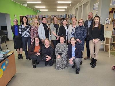 Na zdjęciu znajdują się uczestnicy spotkania. W tle księgozbiór biblioteki.