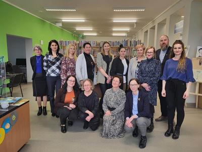 Na zdjęciu znajdują się uczestnicy spotkania. W tle księgozbiór biblioteki.