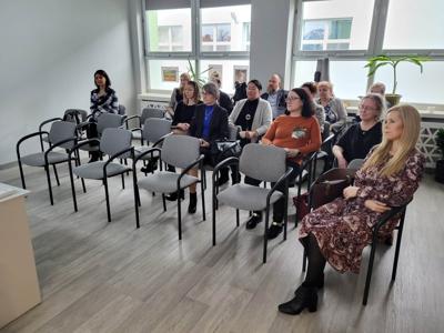 Na zdjęciu znajdują się uczestnicy spotkania. Uczestnicy siedzą na krzesłach.