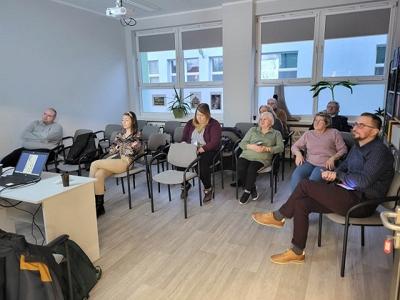 Na zdjęciu znajdują się uczestnicy wykładu. Uczestnicy siedzą na krzesłach.