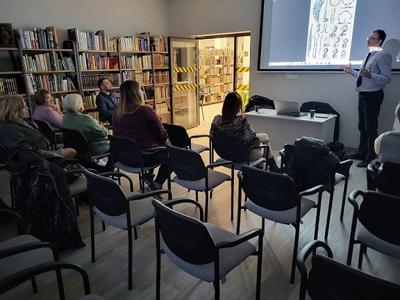 Na zdjęciu znajdują się jedna osoba. Prelegent pokazuje prezentacje multimedialną.