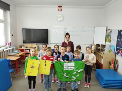 Na zdjęciu znajdują się uczestnicy warsztatów. Dzieci trzymają w ręce prace plastyczne. Zdjęcie wykonano w Szkole Podstawowej w Dębnicy.