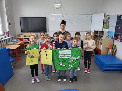 Na zdjęciu znajdują się uczestnicy warsztatów. Dzieci trzymają w ręce prace plastyczne. Zdjęcie wykonano w Szkole Podstawowej w Dębnicy.