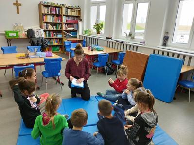 Na zdjęciu znajdują się uczestnicy warsztatów. Dzieci siedzą w kręgu na materacach. Zdjęcie wykonano w Szkole Podstawowej w Dębnicy.