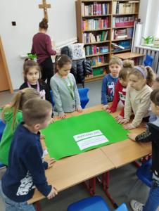 Na zdjęciu znajdują się uczestnicy warsztatów. Dzieci stoją w kręgu. Zdjęcie wykonano w Szkole Podstawowej w Dębnicy.