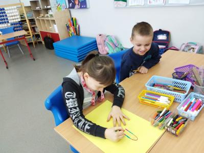 Na zdjęciu znajdują się uczestnicy warsztatów. Dzieci siedzą przy stole i wykonują prace. Zdjęcie wykonano w Szkole Podstawowej w Dębnicy.