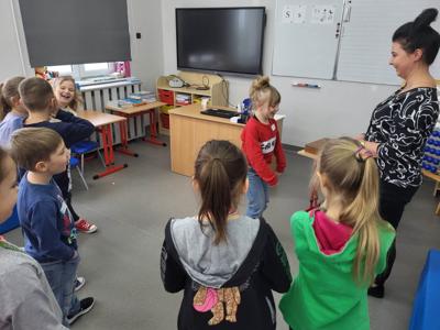 Na zdjęciu znajdują się uczestnicy warsztatów. Dzieci stoją i wykonują zadania. Zdjęcie wykonano w Szkole Podstawowej w Dębnicy.