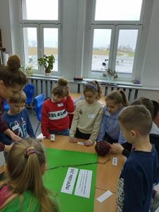 Na zdjęciu znajdują się uczestnicy warsztatów. Dzieci stoją w kręgu. Zdjęcie wykonano w Szkole Podstawowej w Dębnicy.