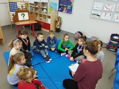 Na zdjęciu znajdują się uczestnicy warsztatów. Dzieci siedzą w kręgu na materacach. Zdjęcie wykonano w Szkole Podstawowej w Dębnicy.