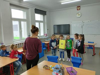 Na zdjęciu znajdują się uczestnicy warsztatów. Dzieci trzymają w ręce prace plastyczne. Zdjęcie wykonano w Szkole Podstawowej w Dębnicy.
