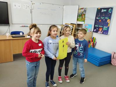 Na zdjęciu znajdują się uczestnicy warsztatów. Dzieci trzymają w ręce prace plastyczne. Zdjęcie wykonano w Szkole Podstawowej w Dębnicy.