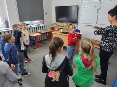 Na zdjęciu znajdują się uczestnicy warsztatów. Dzieci stoją i wykonują zadania. Zdjęcie wykonano w Szkole Podstawowej w Dębnicy.