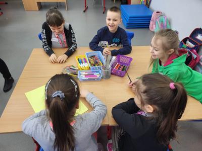 Na zdjęciu znajdują się uczestnicy warsztatów. Dzieci siedzą przy stole i wykonują prace. Zdjęcie wykonano w Szkole Podstawowej w Dębnicy.