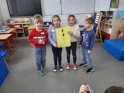 Na zdjęciu znajdują się uczestnicy warsztatów. Dzieci trzymają w ręce prace plastyczne. Zdjęcie wykonano w Szkole Podstawowej w Dębnicy.