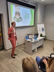 Na zdjęciu znajduje się jedna osoba. Prelegentka prezentuje prezentacje multimedialną.