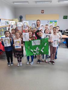 Na zdjęciu znajdują się uczestnicy zajęć. Dzieci trzymają w ręce prace plastyczne.