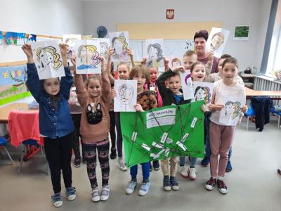 Na zdjęciu znajdują się uczestnicy zajęć. Dzieci trzymają w ręce prace plastyczne.