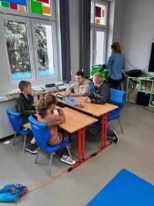 Na zdjęciach znajdują się uczestnicy zajęć. Dzieci siedzą przy stole i wykonują prace plastyczne.