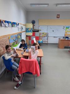 Na zdjęciach znajdują się uczestnicy zajęć. Dzieci siedzą przy stole i wykonują prace plastyczne.