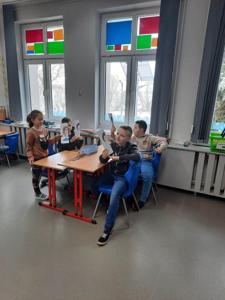 Na zdjęciach znajdują się uczestnicy zajęć. Dzieci siedzą przy stole i wykonują prace plastyczne.