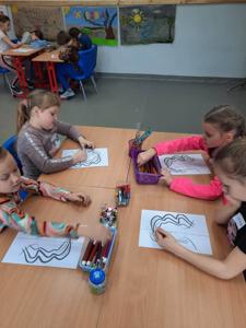 Na zdjęciach znajdują się uczestnicy zajęć. Dzieci siedzą przy stole i wykonują prace plastyczne.