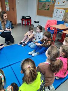 Na zdjęciach znajdują się uczestnicy zajęć. Dzieci siedzą w kręgu na materacach.