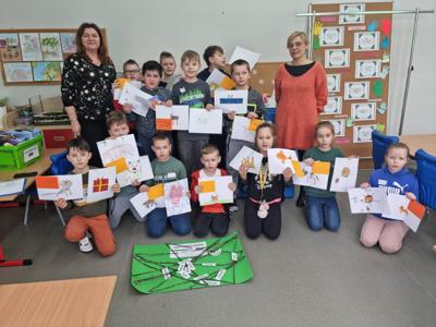 Na zdjęciu znajdują się uczestnicy zajęć. Dzieci trzymają w ręce prace plastyczne.
