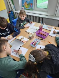 Na zdjęciu znajdują się uczestnicy zajęć. Dzieci wykonują powierzone im zadania.