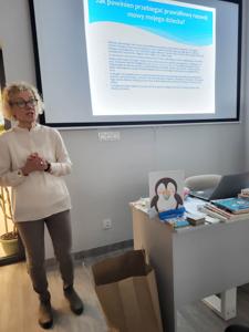 Na zdjęciu znajdują uczestnicy warsztatów. Prowadząca wyświetla prezentacje multimedialną. Zdjęcie wykonano w bibliotece w sali wielofunkcyjnej.
