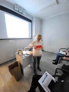 Na zdjęciu znajdują uczestnicy warsztatów. Prowadząca wyświetla prezentacje multimedialną.