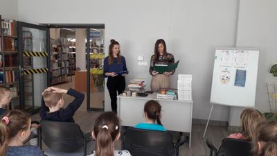 Na zdjęciu znajdują się uczestnicy zajęć. Dzieci siedzą na krzesłach. Zdjęcie wykonano w sali wielofunkcyjnej biblioteki.