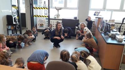 Na zdjęciu znajdują się uczestnicy zajęć. Dzieci są w kręgu. Zdjęcie wykonano w bibliotece.