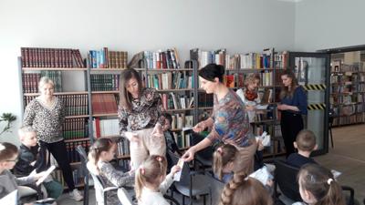 Na zdjęciu znajdują się uczestnicy zajęć. Dzieci siedzą na krzesłach. Zdjęcie wykonano w sali wielofunkcyjnej biblioteki.