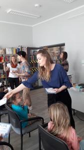 Na zdjęciu znajdują się uczestnicy zajęć. Dzieci siedzą na krzesłach. Zdjęcie wykonano w sali wielofunkcyjnej biblioteki.