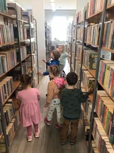 Na zdjęciu znajdują się uczestnicy zajęć. Dzieci trzymają w rękach dyplomy i książki. Zdjęcie wykonano w bibliotece.
