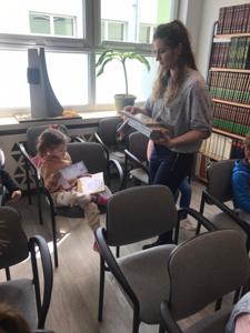 Na zdjęciu znajdują się uczestnicy zajęć. Dzieci siedzą na krzesłach. Zdjęcie wykonano w bibliotece.