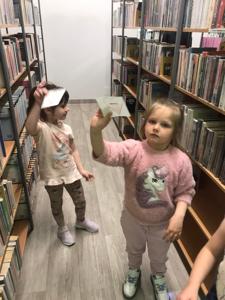 Na zdjęciu znajdują się uczestnicy zajęć. Dzieci trzymają w rękach dyplomy i książki. Zdjęcie wykonano w bibliotece.