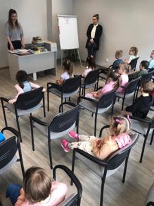 Na zdjęciu znajdują się uczestnicy zajęć. Dzieci siedzą na krzesłach. Zdjęcie wykonano w bibliotece.